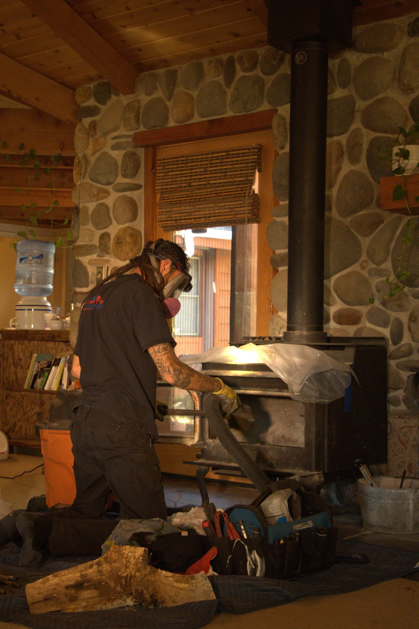 A technician vacuuming ash from a wood stove