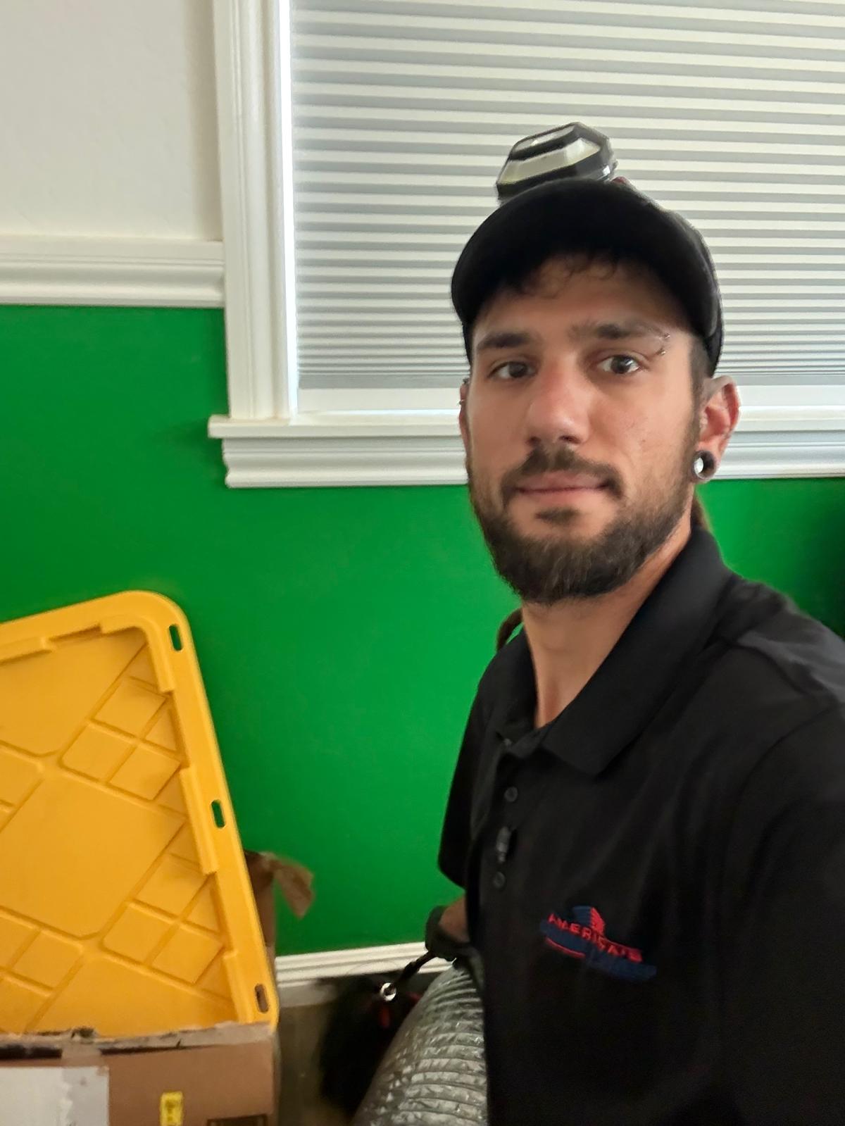 Michael indoors in a black Americas Chimney Sweep polo and a cap with a headlamp