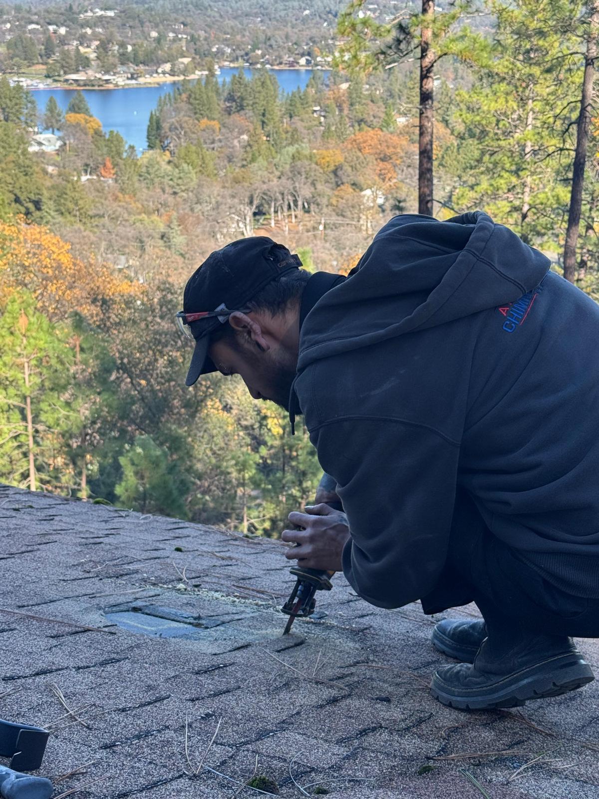 Michael crouched on a shingle roof driving a screw into a roof penetration